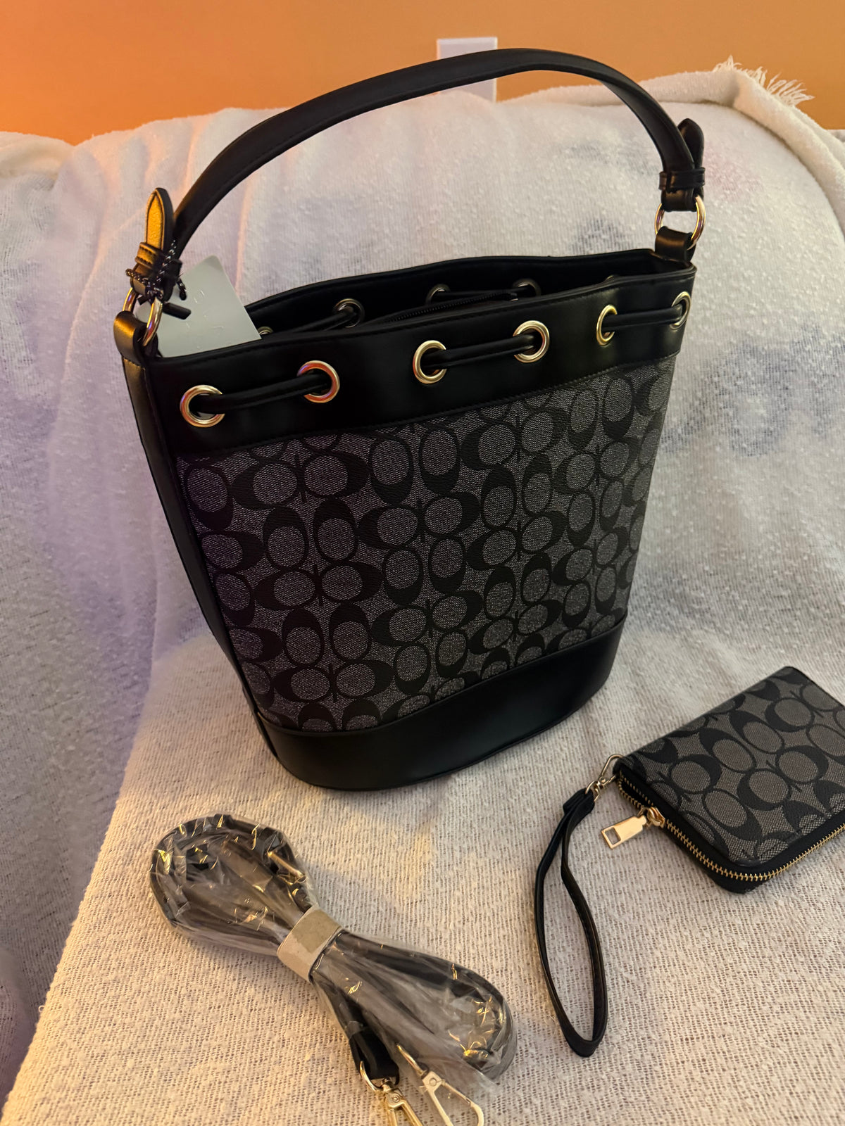 Black monogram bucket bag with varsity stripe detail, wristlet wallet, and crossbody strap